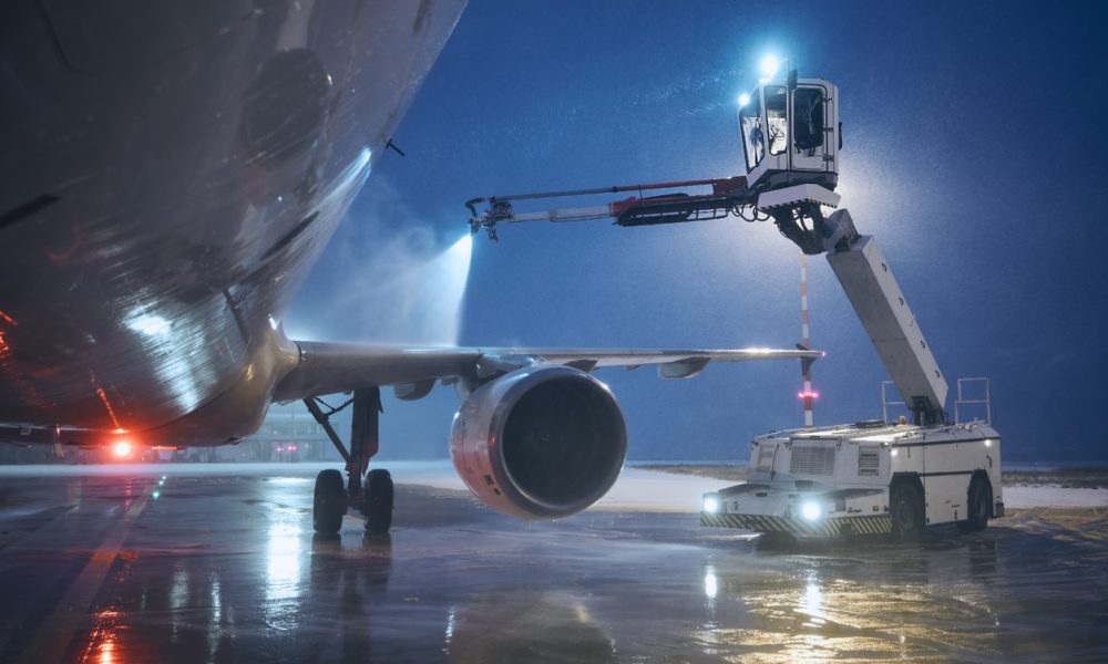 Deicing of airplane before flight. Winter night at airport during snowfall.